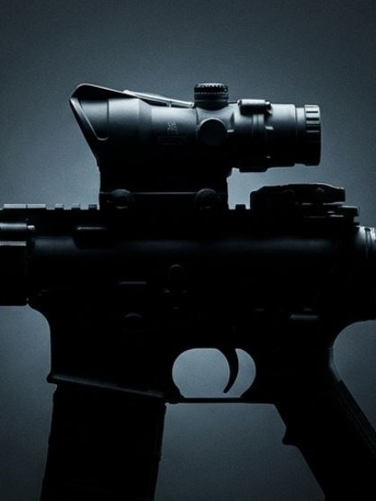 Silhouette of a tactical rifle with a mounted scope against a dark background, emphasizing its sleek design.